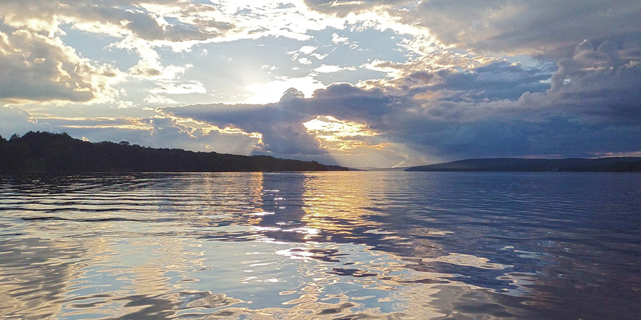 Cloud obscured sun and calm river.